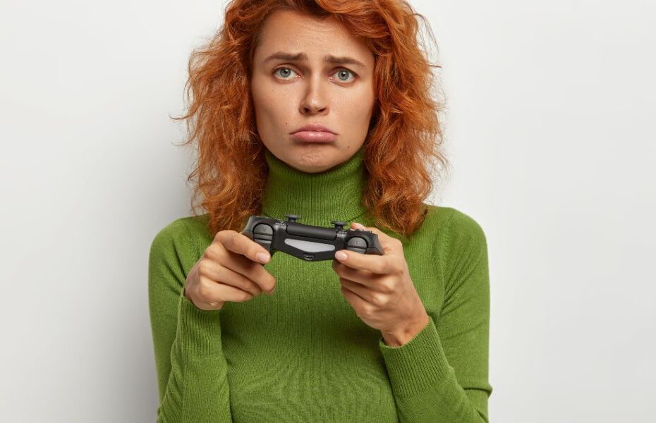 Mulher com um controle de videogame na mão e com expressão de infelicidade devido a um jogo ruim.