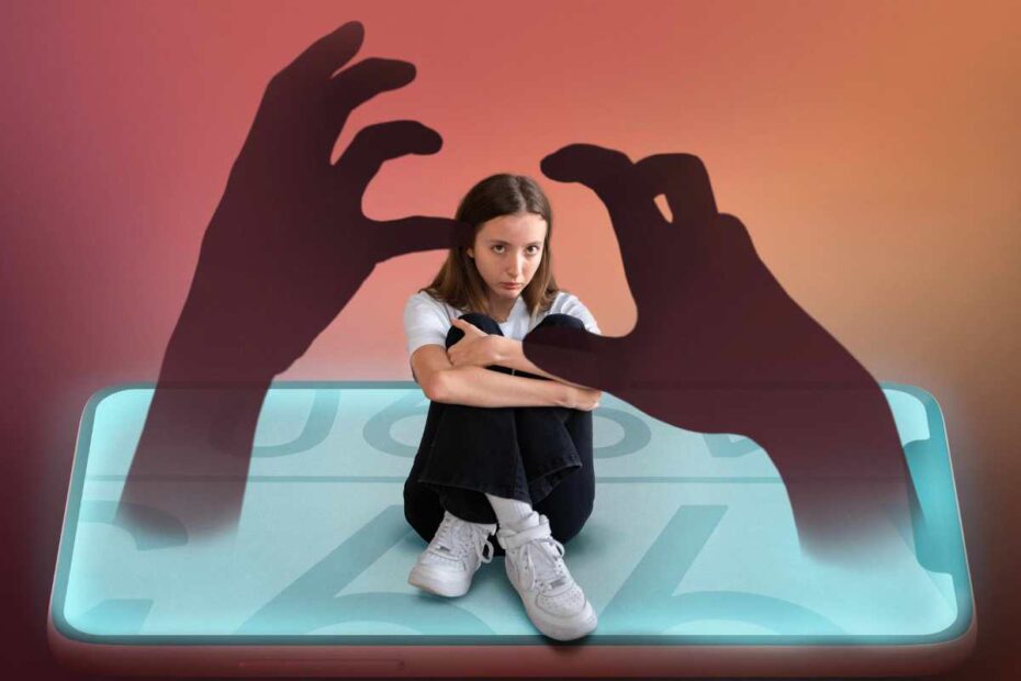 Edição de uma adolescente com semblante chateado sentada em um smartphone. Do aparelho está saindo duas sombras de mãos que a circundam, em alusão ao bullying digital ou cyberbullying.